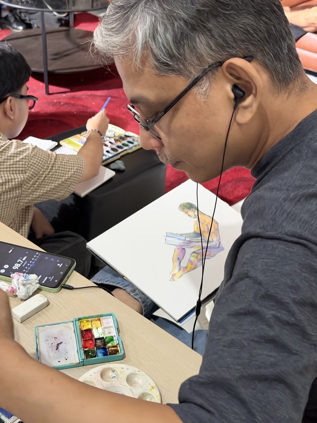 An artist paints a watercolour figure during the Room 202 session